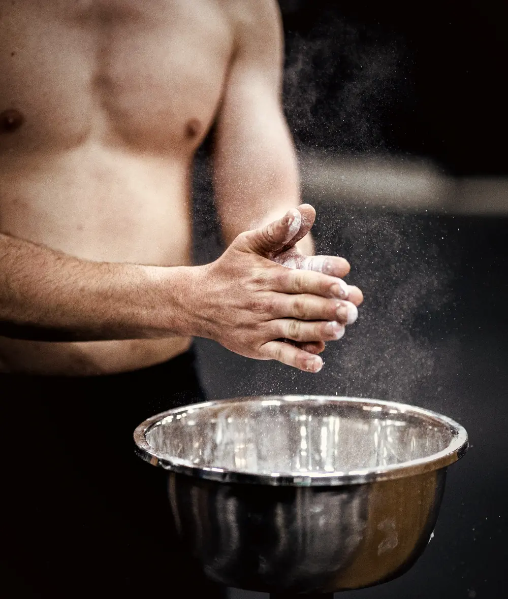 Hands clapping chalk dust over a gym chalk bowl