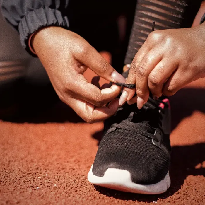 Lacing up shoes on a red running track